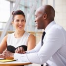Male and female business professional smiling and looking over documents