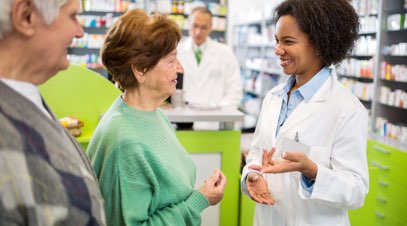 Female pharmacist speaking with patients in pharmacy-alt-text
