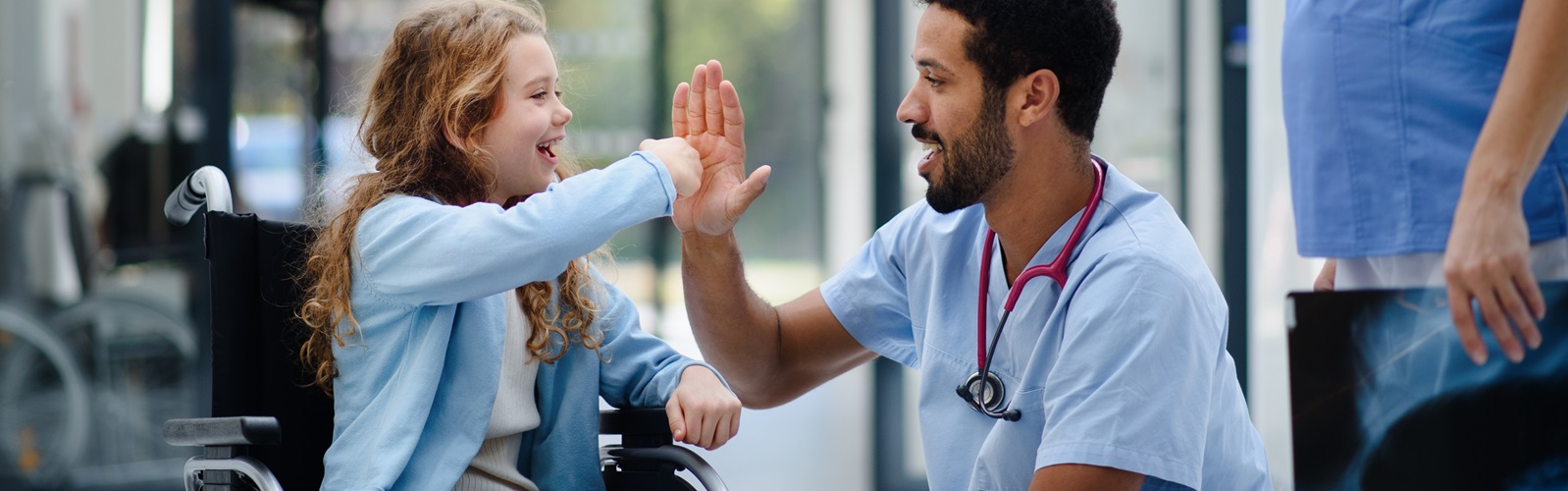 small female child in a wheelchair high fiving with a male nurse