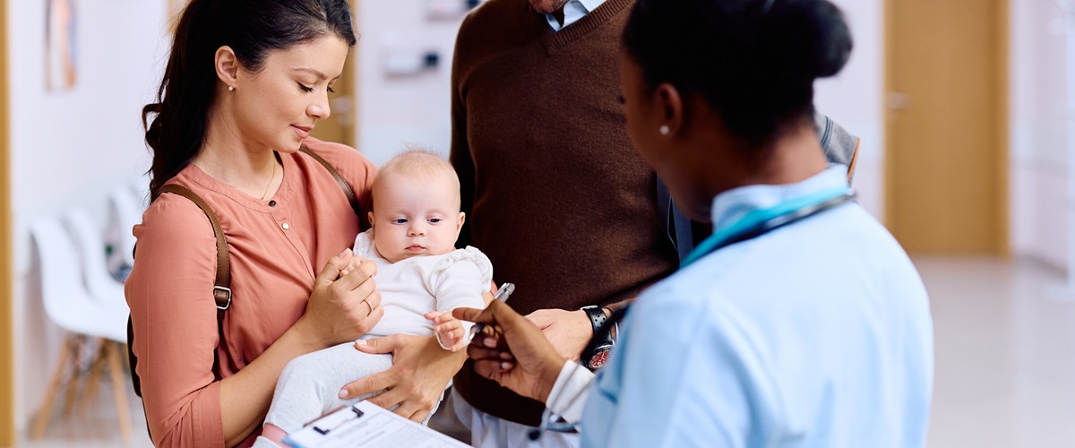 couple holding a baby speaking to their nurse in a hospital