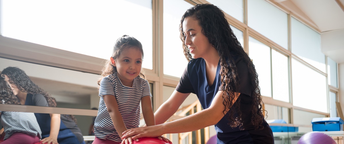 young girl working with a female occupational therapist in a gym setting