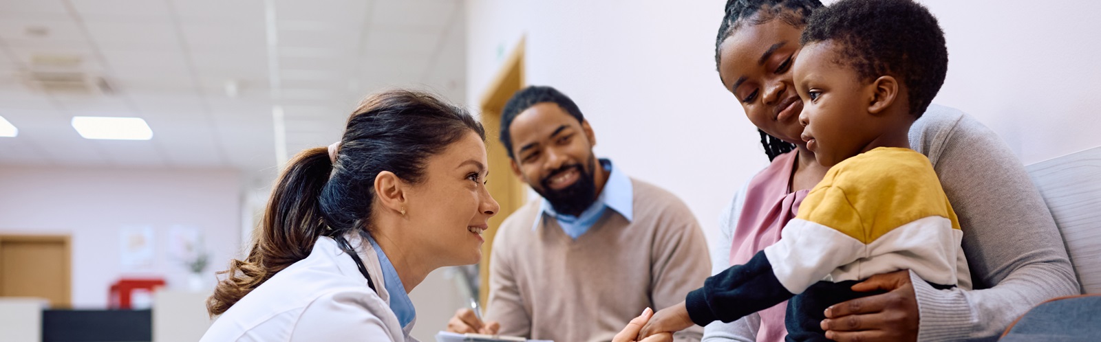 female hospital professional speaking with a young boy and his parents in a hallway