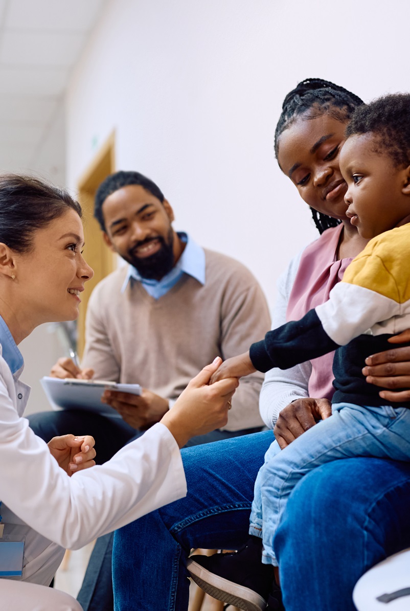 female hospital professional speaking with a young boy and his parents in a hallway