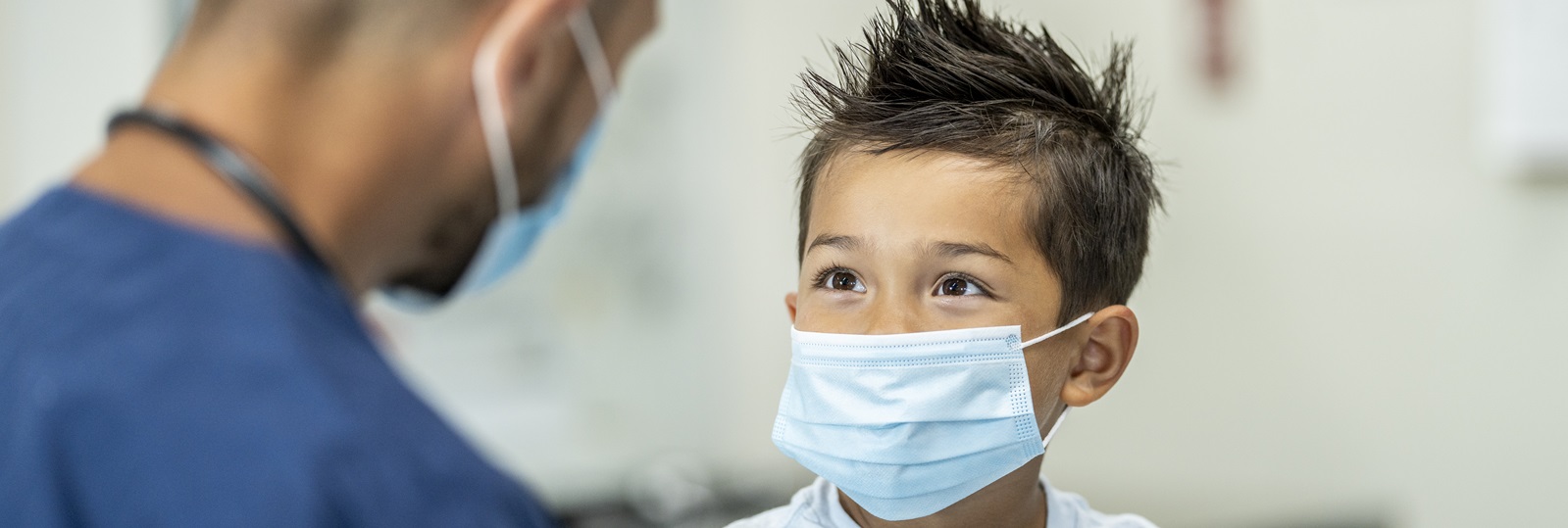 male healthcare personnel speaking with a young boy writing down information on a medical chart