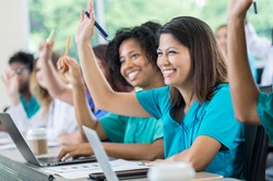 Group of nursing student raising their hands while they sit in a classroom 