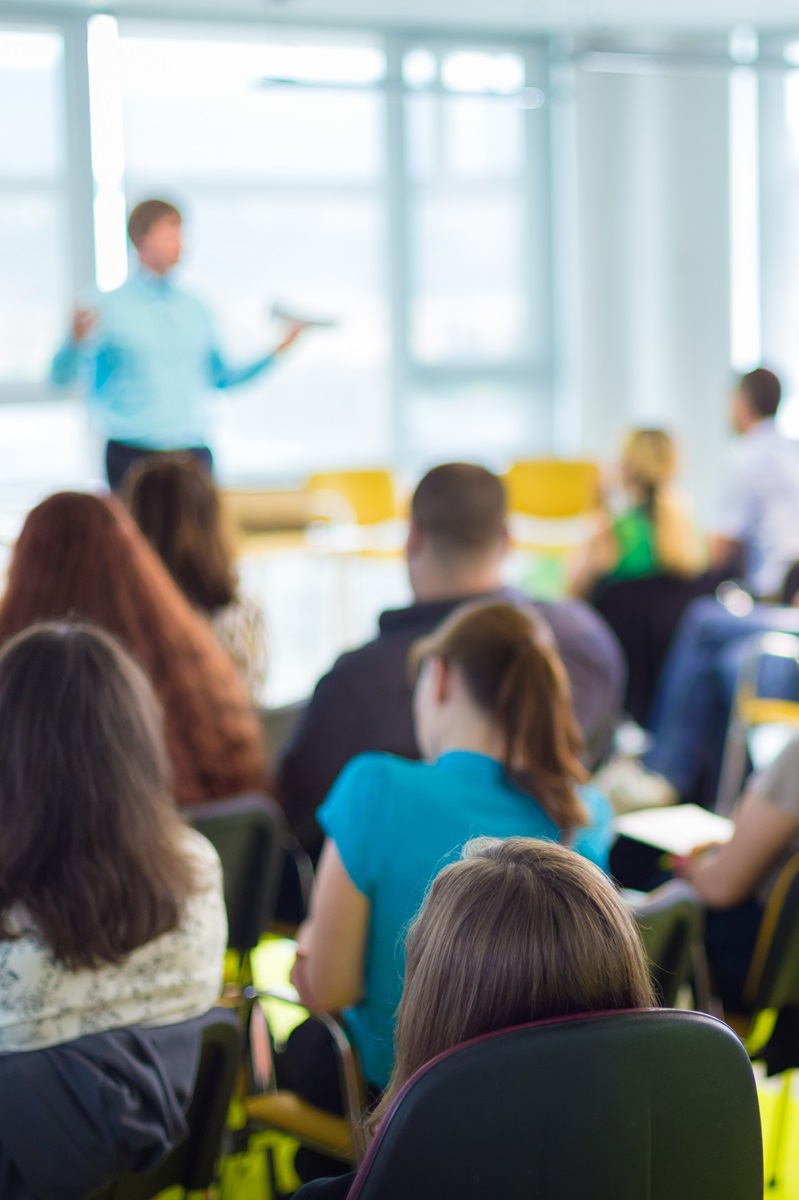 variety of adults sitting in a class room listening to an instructor give a presentation