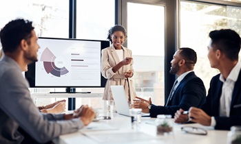 one woman person of color presenting a graph to several male colleagues