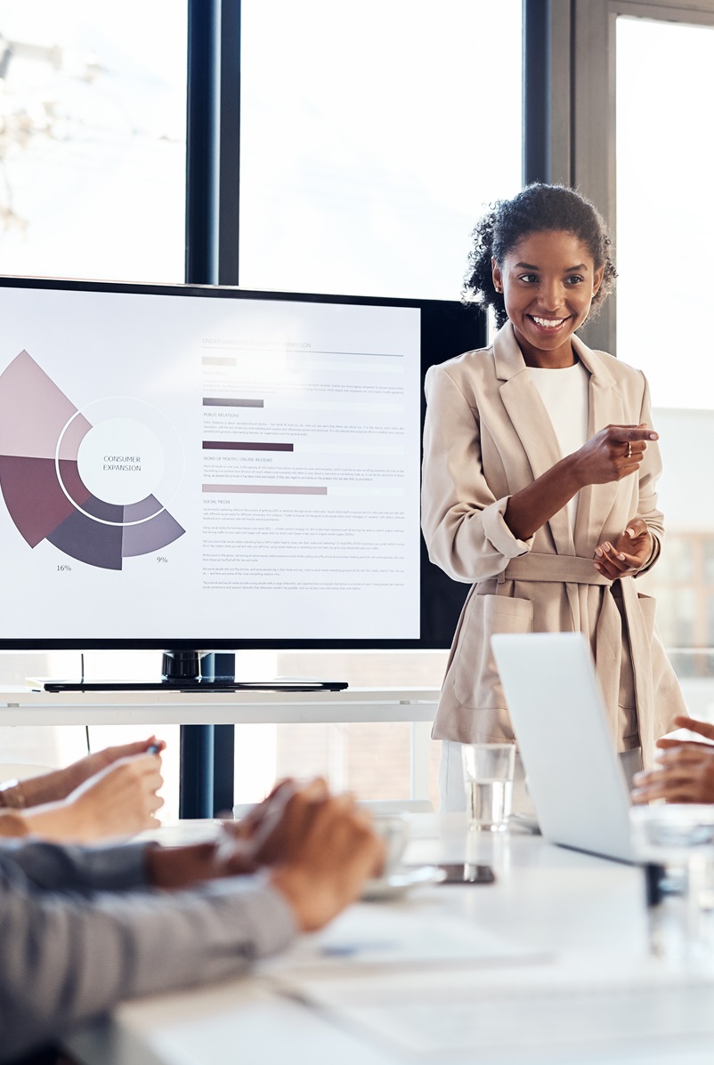 one woman person of color presenting a graph to several male colleagues