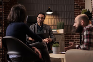 counselor meeting with a man on a couch and woman in a chair in an office