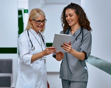 two women healthcare workers discussing findings on a tablet