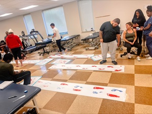 men and women in a physical therapy classroom working on gait lab