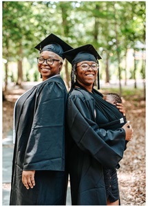 Szhanesha, and her baby, and Shirley Becoat standing back to back in a wooded park in their cap and gowns