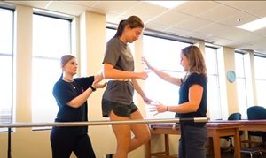 three female physical therapy students practicing therapy lessons in the classroom