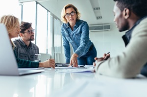 group of male and female professionals discussing a project in a conference room