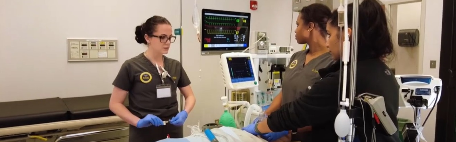 three healthcare workers studying the administration of anesthesia in a hospital room setting