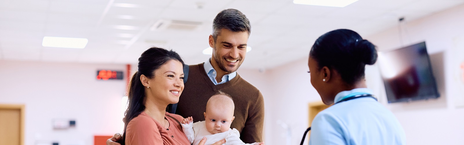 mother, father, and baby are meeting with their nurse in a hospital