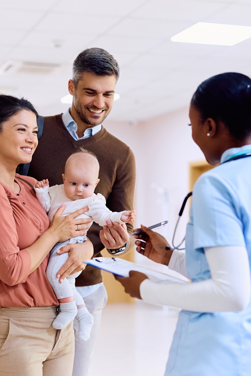 mother, father, and baby are meeting with their nurse in a hospital