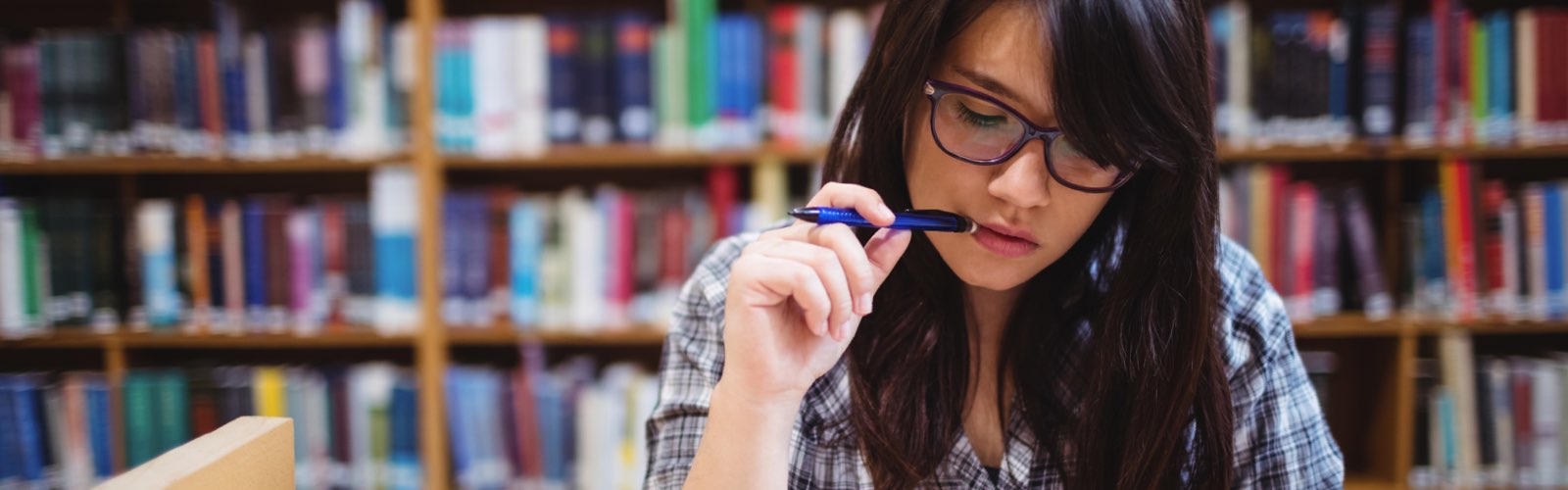 Female student in library reviewing programs