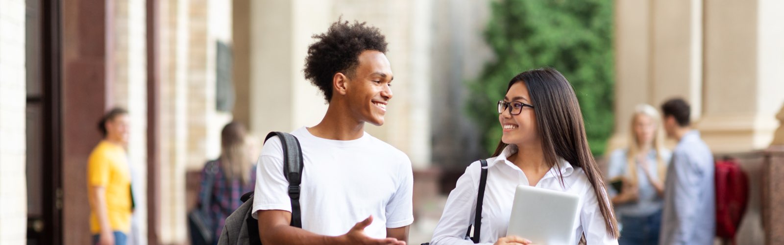 Male and female student talking on college campus