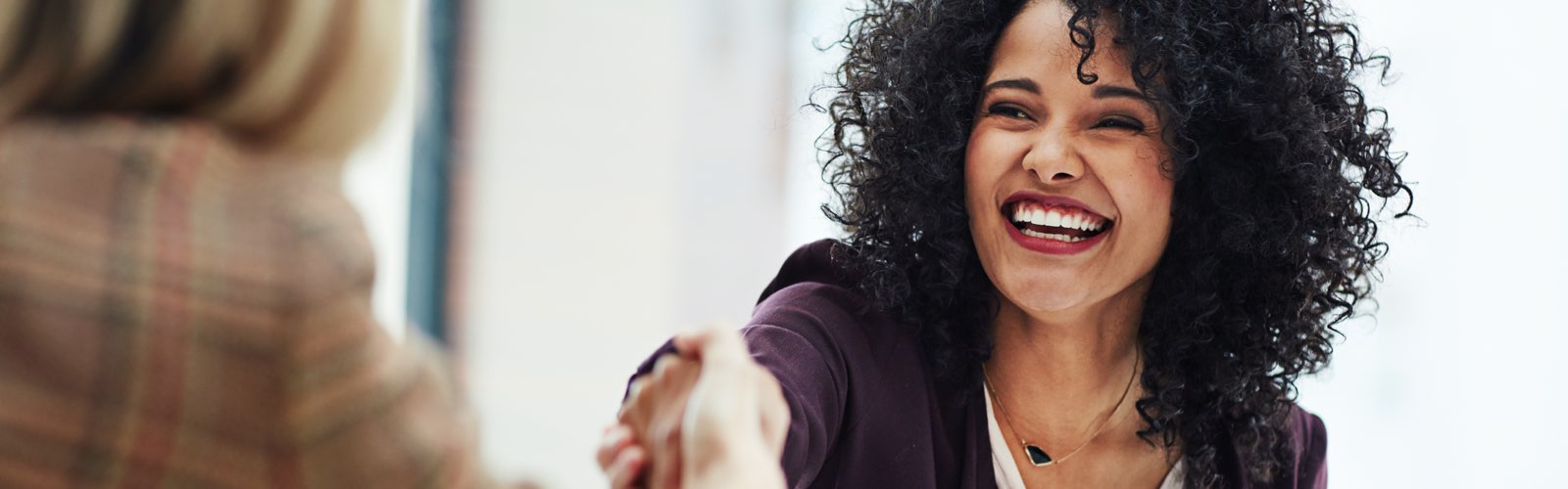 Smiling female human resources professional shaking job applicant's hand