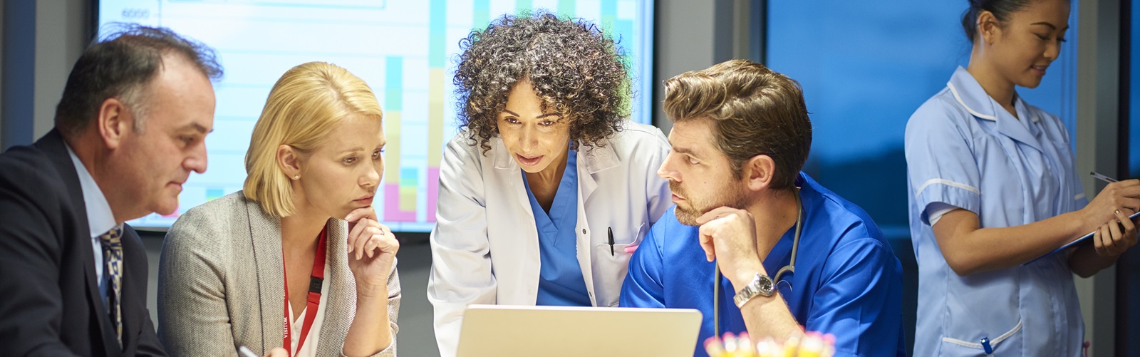 group of doctors and healthcare administrators discussing a project while looking at a laptop