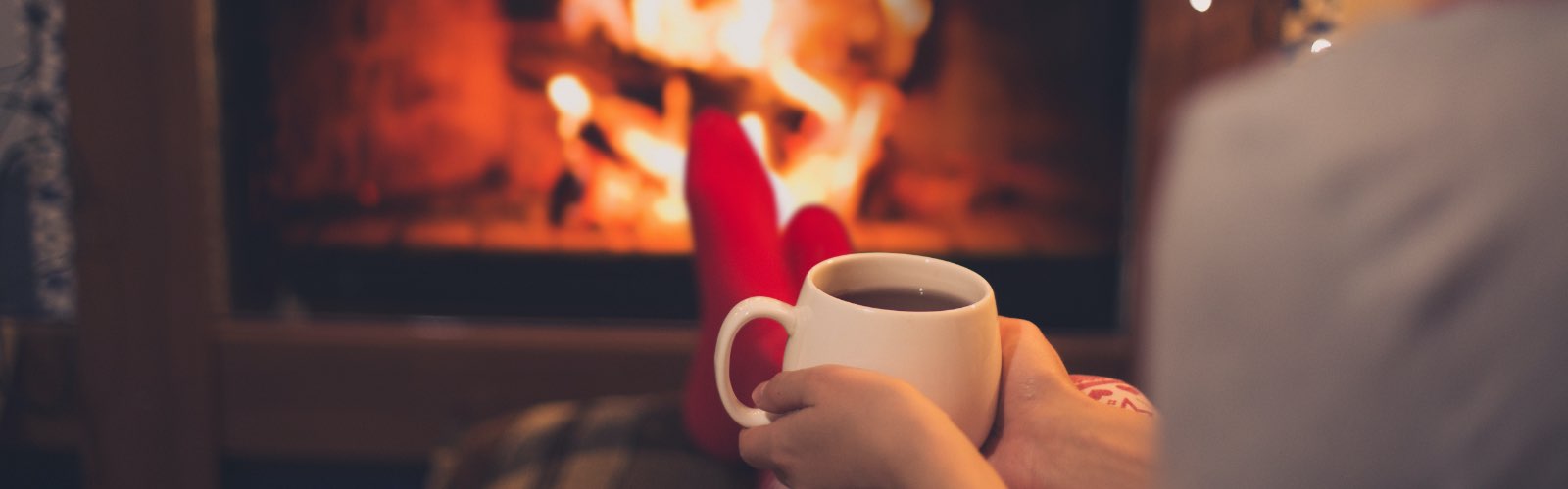 Woman sitting in front of fire drinking tea