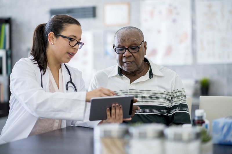 physician assistant showing a patient some information on a tablet