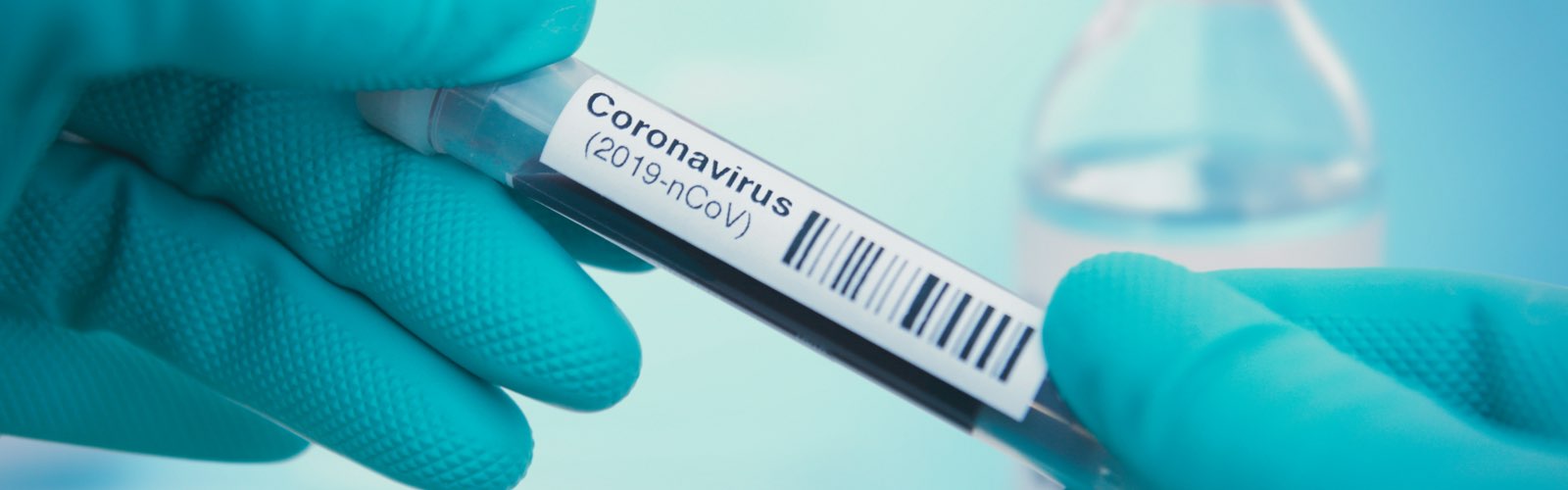 Gloved hands holding coronavirus sample vial in lab