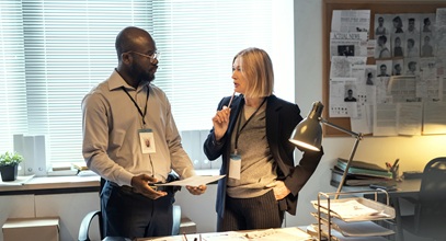 man and a woman intently discussing the paperwork on the desk