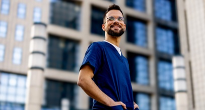 man wearing blue scrubs standing in front a building