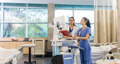 female doctor and nurse looking at a computer in a patient's hospital room