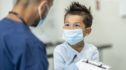 male healthcare personnel speaking with a young boy writing down information on a medical chart